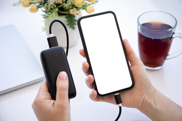 Woman hands hold phone with isolated screen connected to powerbank