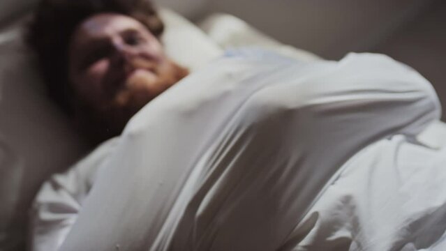 Selective focus shot of young male patient wearing straitjacket lying on hospital bed trying to free his handsSelective focus shot of young male patient wearing straitjacket lying on hospital bed tryi