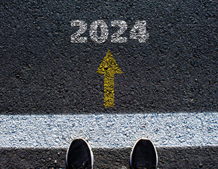 Someone standing on a asphalt road with 2024 year lettering on it. New year new beginning concept.