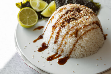 Close-up, rice topped with sauce and sprinkled with sesame seeds.