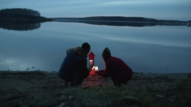 People at dusk by the lake launch festive rockets. Romantic evening.