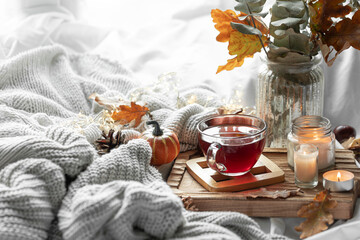 Autumn composition with a cup of tea, leaves and a knitted element.