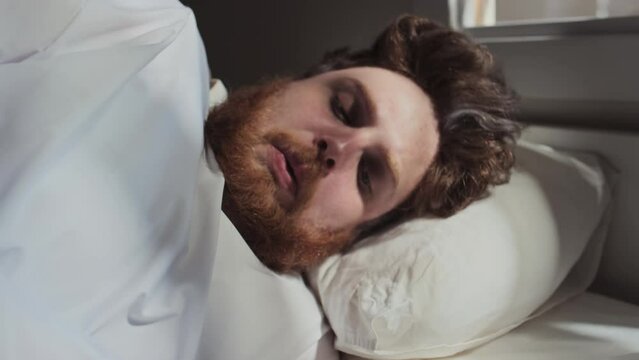 Portrait of young Caucasian man waking up in hospital ward, seeing straitjacket on him and getting anxious