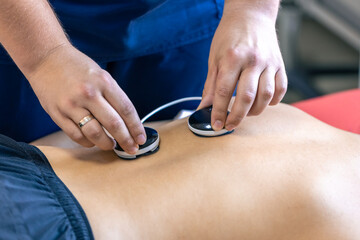 Woman receiving myostimulation treatment in physical therapy clinic.