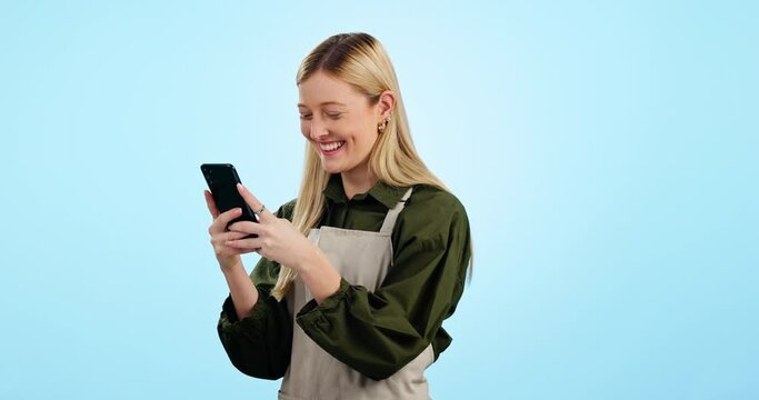 Business owner, waitress and woman with phone for social media, funny networking and cafe chat in studio. Young entrepreneur, barista or coffee shop typing on mobile and laughing on a blue background