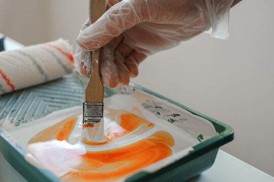 painter mixes paint in a tray before painting the walls