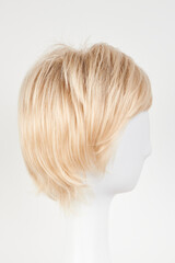 Obraz premium Natural looking blonde fair wig on white mannequin head. Short hair cut on the plastic wig holder isolated on white background, side view.