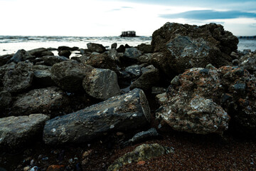 Low light with shadow of big pile of rocks. There are many old shells attached to it. During the evening time by the sea