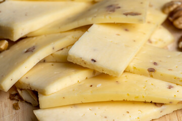 Sliced piece of milk cheese with walnuts