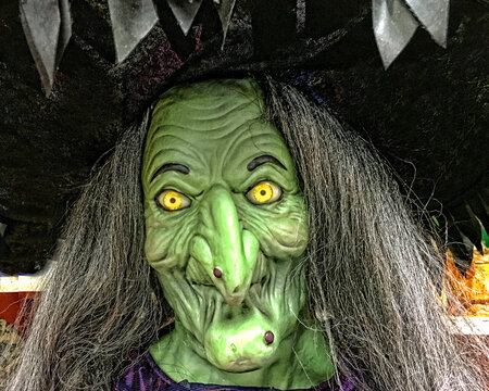 Green head shot of scary and spooky old witch with yellow eyes