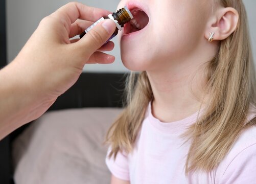 A Child Taking Vitamin D Drops In His Mouth From A Dropper. BAD. Ingestion Of Vitamins C, D For The Treatment And Strengthening Of Skin, Hair And Nails