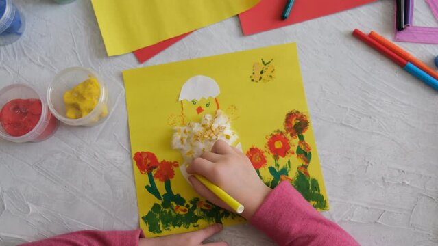   Children's creativity. Child making card with Easter chick from colorful paper and cotton pad. Handmade. painting and drawing