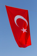 Turkish flag hanging outdoor against blue sky