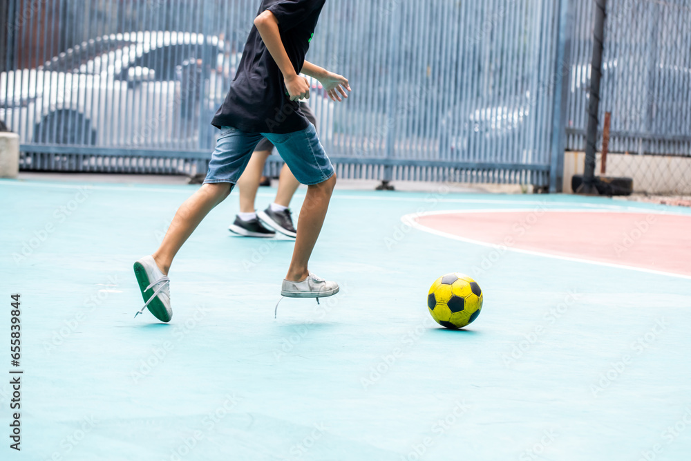 Wall mural Selective focus to yellow ball with blurry futsal player playing.