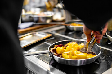 Chef cook hand cooking potato and meat food in pan at the restaurant kitchen