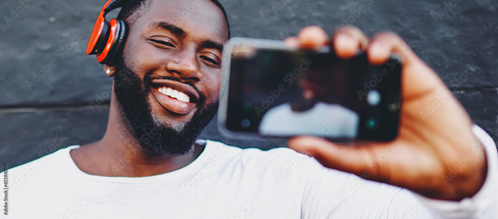 Poster smiling male hipster making video call using internet connection on cellular while phoning