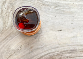 glass with whiskey and ice cube with coctail chery on a grey background top view