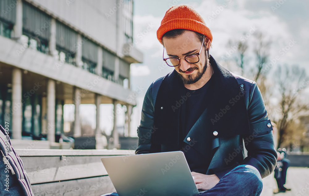Poster stylish caucasian male blogger updating software on laptop computer for installing new application