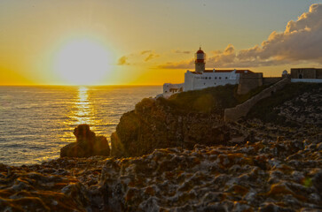 
red lighthouse at sunset on a cliff overlooking the ocean