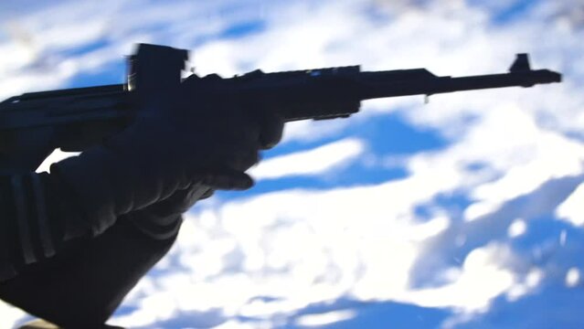 a male soldier reloading the machine gun at night in winter, a robber is a bandit , an armed terrorist is fighting