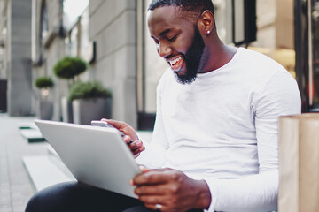 Cheerful afro american hipster guy happy about getting discount on email for shopping in web store