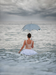 Fototapeta premium A ballerina with gold goes into the sea. Art concept.