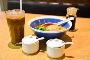 Clear soup ramen with delicious meat pieces in a ceramic bowl​  and expresso iced coffee