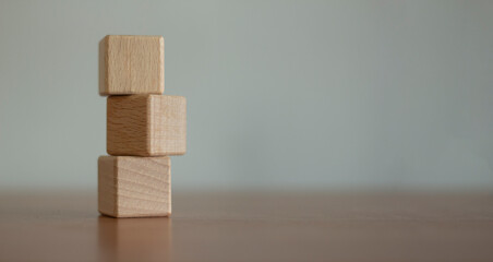 Three blank wooden blocks stacked on a blurred background.