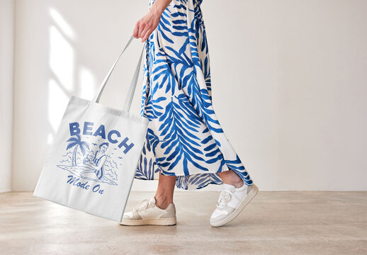 Mockup of woman holding customizable tote bag, low section