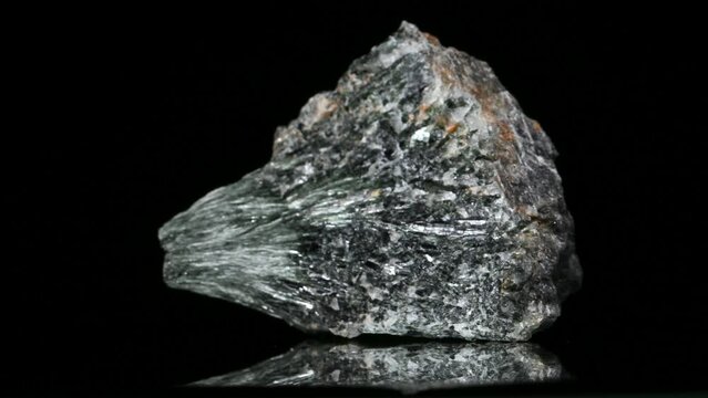 Actinolite [calcium silicate hydroxide] specimen rotating slowly against a black background.
