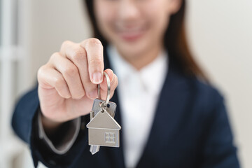 Close up view realtor broker holding home keychain in her hand and showing to new owner.