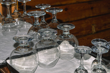 Washed glassware dries on the table. Transparent glasses are dried upside down. Tableware for drinking drinks. Glare on clean and wiped transparent dishes from drops.