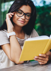 Fototapeta premium young caucasian woman fond of literature satisfied with interesting book on coffee break