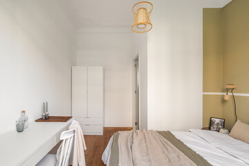 Cozy hotel room in light beige tones with a double bed and a table with a chair. Comfortable and...