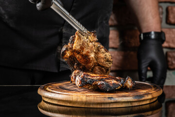 The chef puts fried pork meat on a wooden board on a dark background