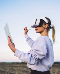 Woman in VR headset using touchpad and stylus for virtual reality