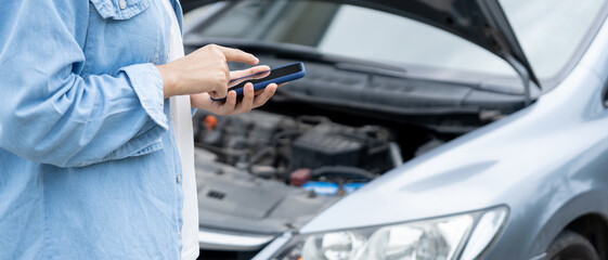 breakdown, broken car, repair. Woman uses mobile phone check insurance premiums through application...