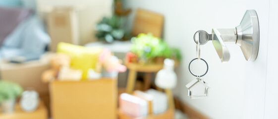 Moving house, relocation. The key was inserted into the door of the new house, inside the room was a cardboard box containing personal belongings and furniture. move in the apartment or condominium
