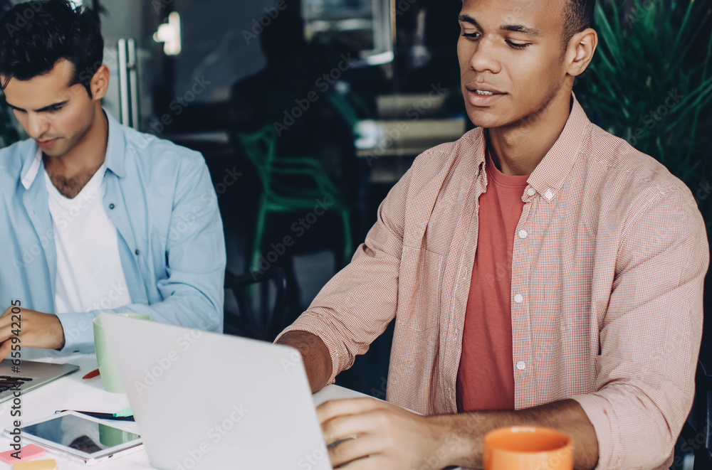 Poster skilled young men updating software and database on new modern netbooks