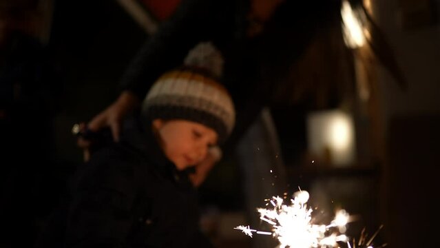 Little boy holding sparkler in slow motion during December holidays