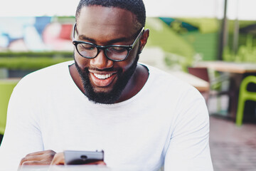 Happy male blogger in stylish eyewear checking statistics of account in social networks