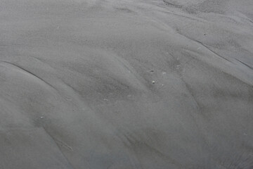 An abstract background of wet sands at the beach. Grainy texture of sands surface with copy space...