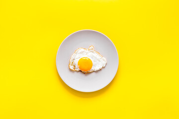 Fried egg on white plate, top view. Food background