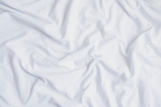Crumpled white sheet seen from above. White fabric texture and background