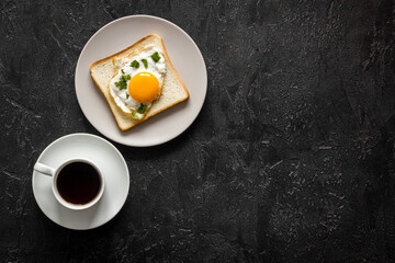 Fried eggs on toast bread and cup of black coffee, top view