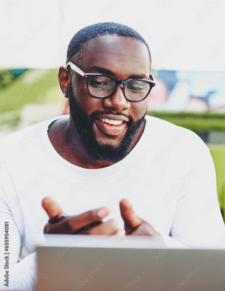 Poster successful dark skinned hipster guy enjoying time for chatting via web camera