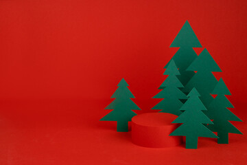 Christmas tradition background with red scene, cylinder podium mockup for presentation gifts, cosmetic products, good surrounded green paper spruce forest. New year template for card, poster, flyer.