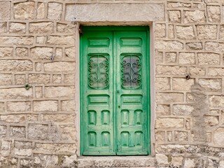 Vintage village door of faded green colour on stone wall in Patones, Madrid community, Spain. Wooden cosy front door