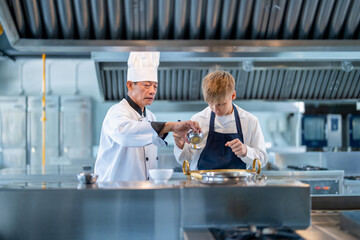 Fototapeta na wymiar Senior male chef teaches young teenage boys cooking in school kitchen. Education Concept
