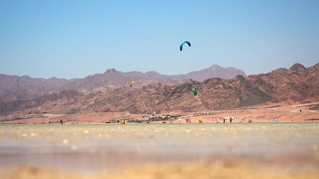 Surfers on the kiteboard with colored parafoil wings catching the flow of wind. Kitesurfing in Dahab lagoon. Best Kiteboarding Spots Worldwide